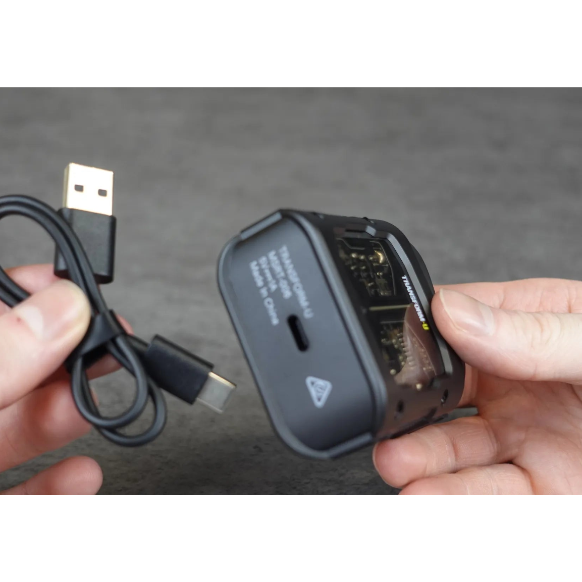 Person holding a USB-C cable and a travel shaver against a gray background