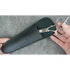 Scissors in a black sheath held by hands against a gray background