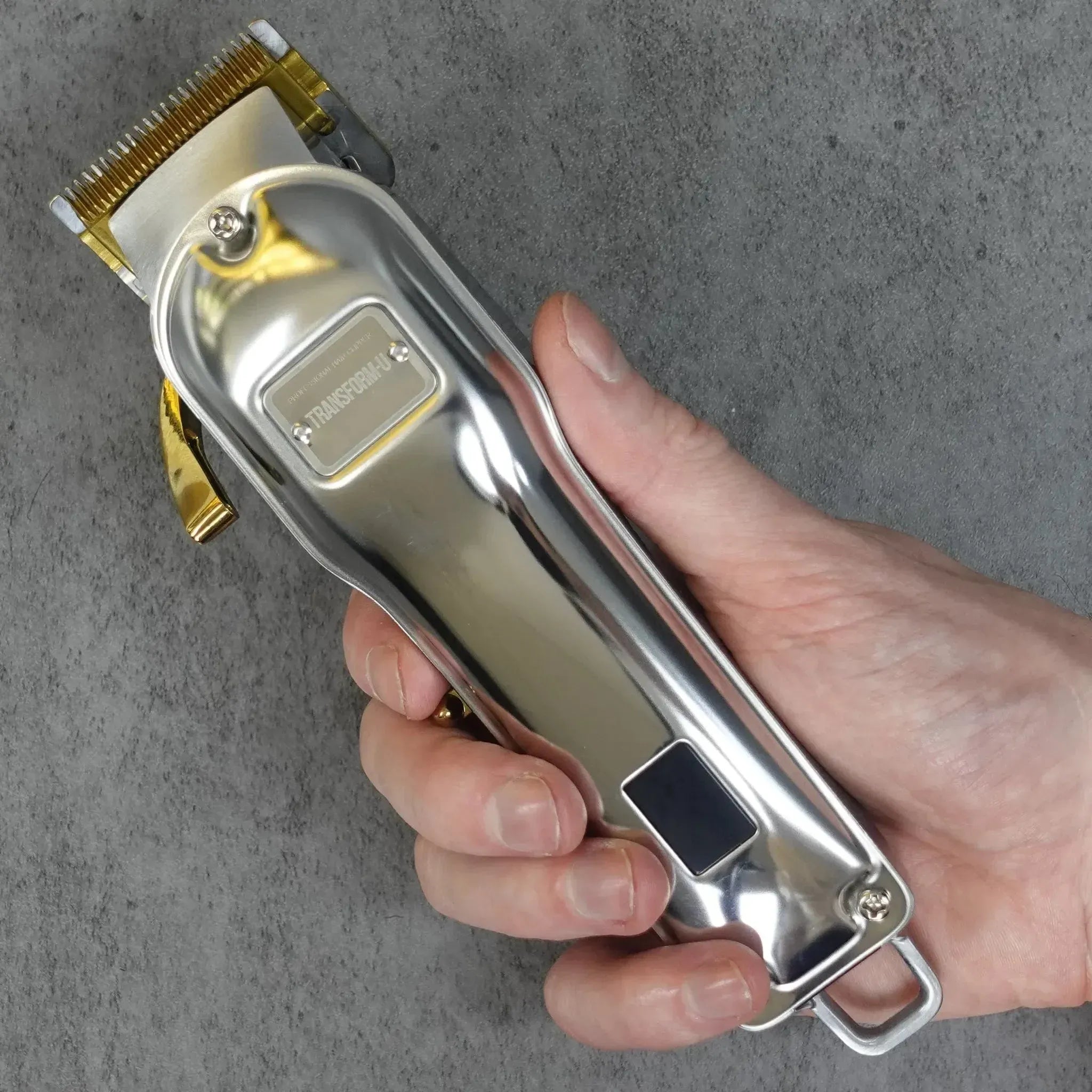 hand holding a silver hair clipper on a gray background