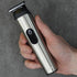 Hand holding a silver and black hair trimmer against a gray background
