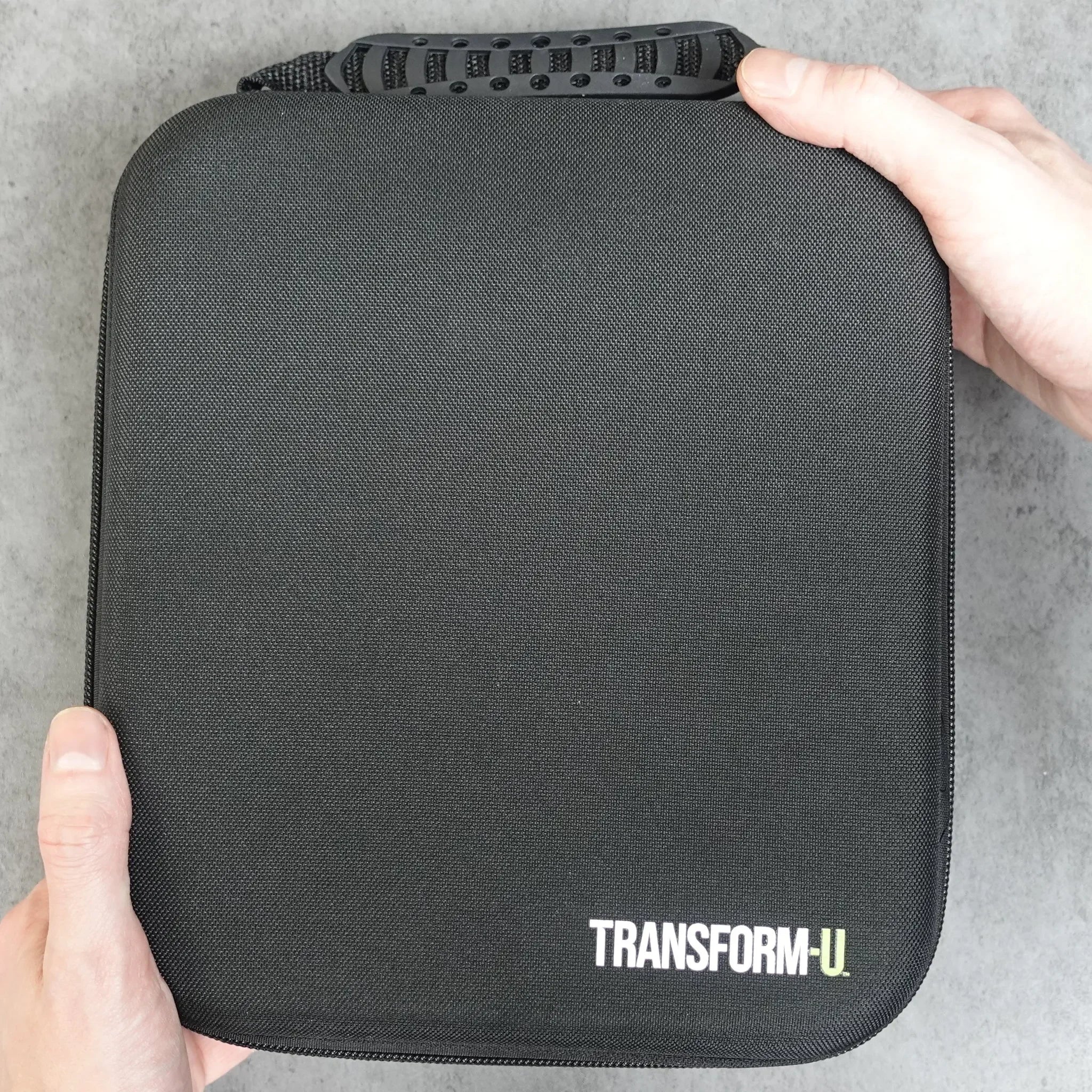 Black carrying case with 'TRANSFORM-U' branding held by a person on a light gray background