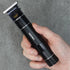 Hand holding a black hair trimmer with 'TRANSFORM-U' branding on a gray background