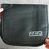 Black toiletry bag held by hands on a light gray surface