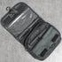 Black travel toiletry bag with clear compartments on a light gray surface