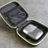 Black electric shaver in a carrying case with a cable on a gray surface