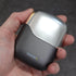 Hand holding a black and silver travel shaver with 'Transform-U' branding on a dark background