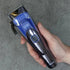Hand holding a blue and black hair clipper on a gray background
