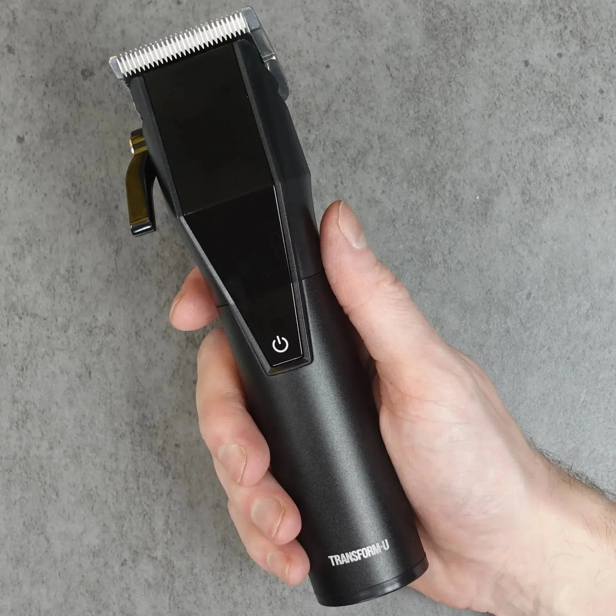 Hand holding a black hair clipper against a gray background