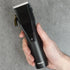 Hand holding a black hair clipper against a gray background