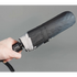 Hand holding a black umbrella against a gray background