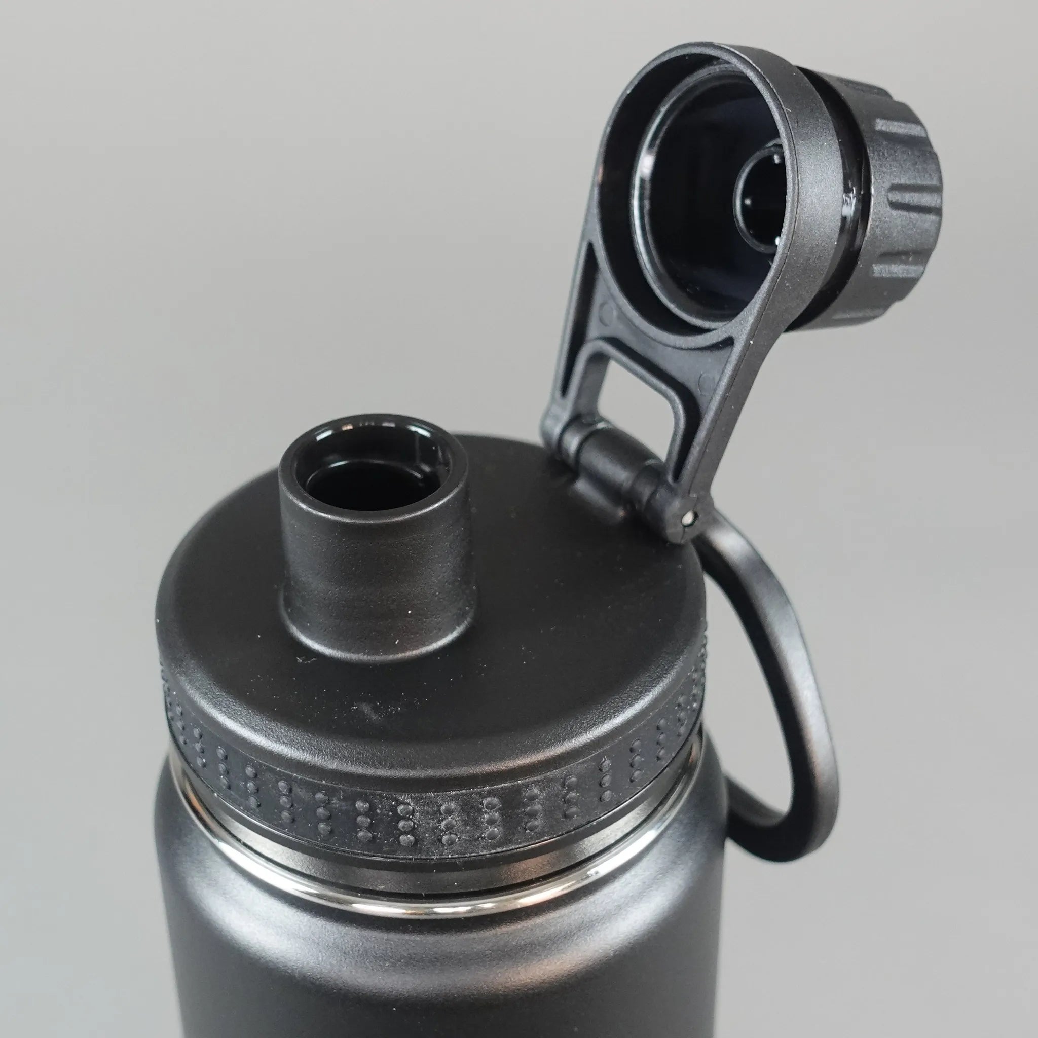 Close-up of a black water bottle with a metallic cap on a light gray background