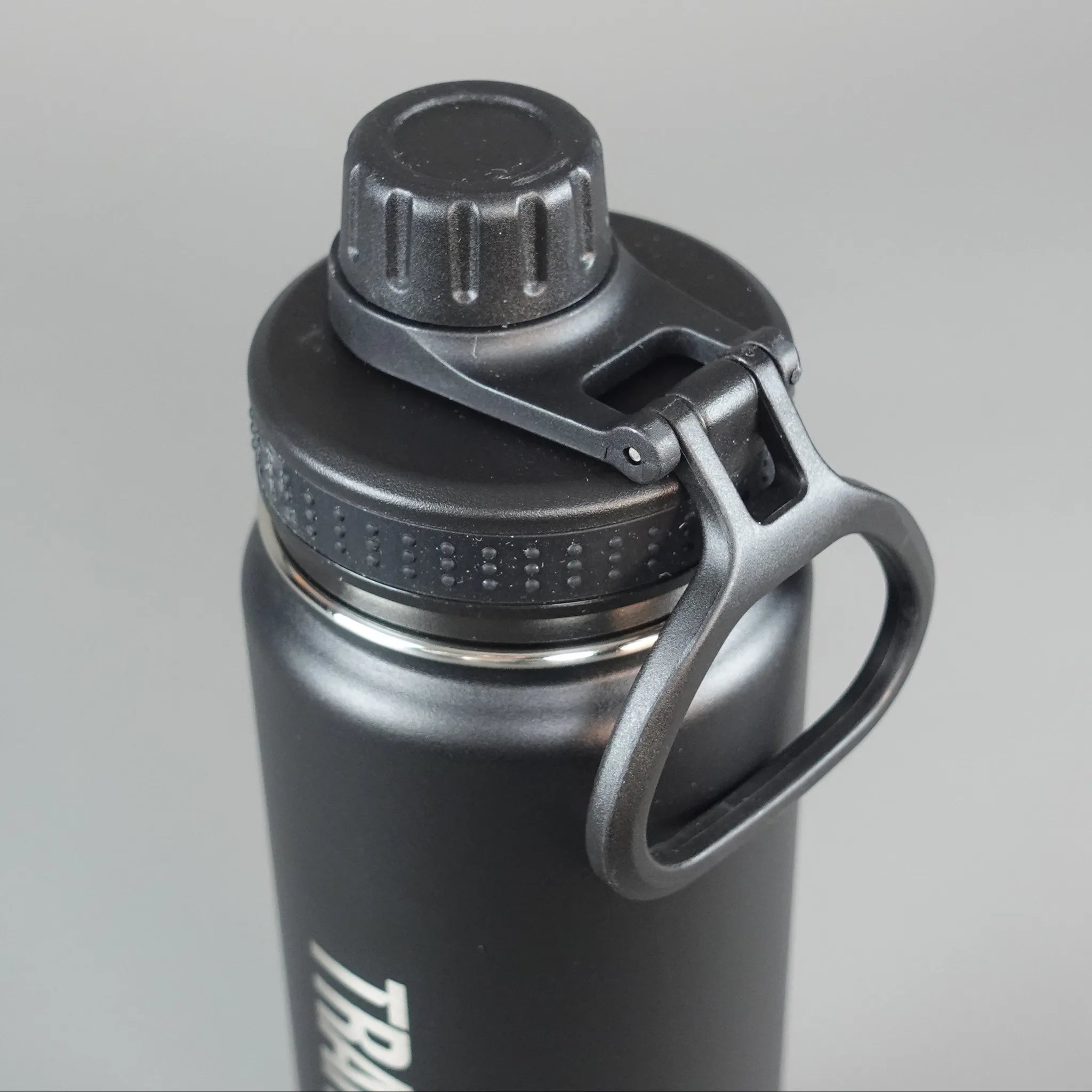 Black insulated water bottle with a handle on a gray background